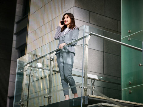 young asian businesswoman making a call using mobile phone inside modern office building