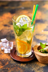 Homemade lemonade in a glass, lime, lemons and mint on a wooden board.
