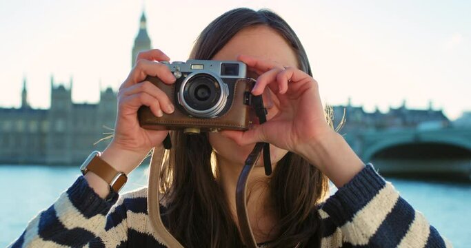 A young woman taking a photo on her camera on holiday in London