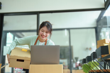 A portrait of a small startup, an SME owner, an Asian female entrepreneur checking orders to arrange the produce before packing the products in the inner boxes with the customers. Freelance concepts