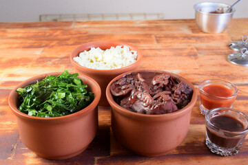 Feijoada typical Brazilian food, beans with pork bacon, orange rice and flour, chili sauce and crackling