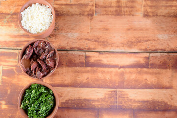 Feijoada typical Brazilian food, beans with pork bacon, orange rice and flour, chili sauce and crackling