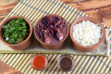Feijoada typical Brazilian food, beans with pork bacon, orange rice and flour, chili sauce and...
