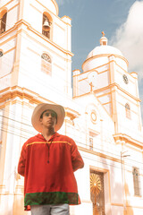 Latin teenager with classic clothes and hat from Nicaragua and the traditional dance from Latin America in front of the cathedral church of Jinotega - obrazy, fototapety, plakaty