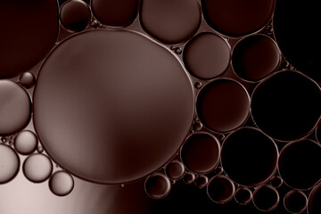 Abstract oil droplets on water surface creating bubbles and circle pattern  with chocolate brown effects background.	
