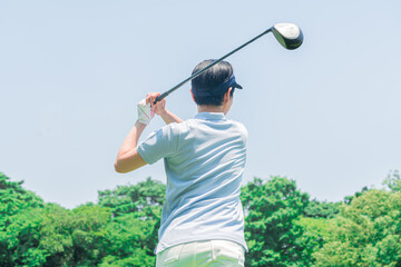 スイングをするゴルフウェアを着た日本人女性