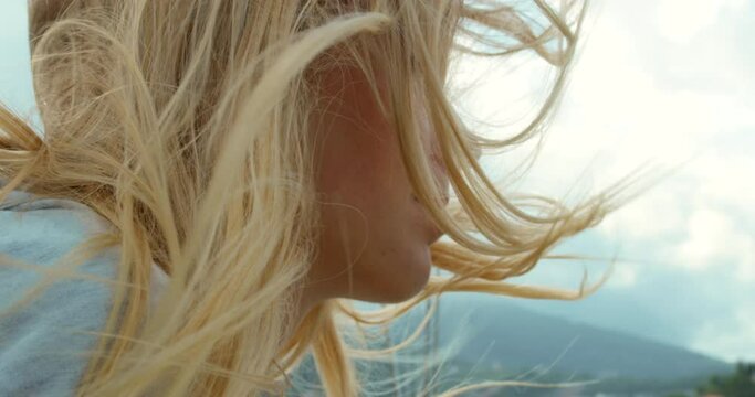 Closeup of a blonde woman with her hair blowing in her face on a windy day on a yacht. Young woman with her hair blowing in the wind around her face during a cruise