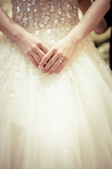 Bride hand with a wedding ring on the background of dress