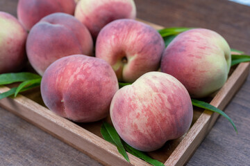 Fresh Sweet Peach on wooden background, Pink and yellow Peach fruit with leaf on wooden plate.