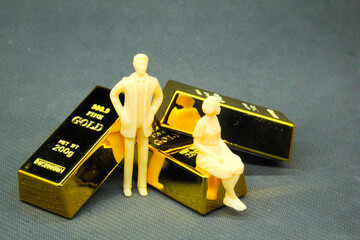 small men and women with a background of three 200g gold nuggets. the concept of wealth