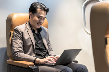 Asian businessman using computer labtop working during business trip on plane, Airline business