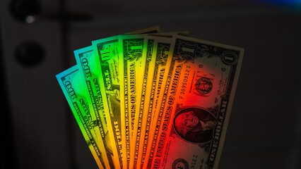Rays of a rainbow on a man's hand with a bundle of dollars. 