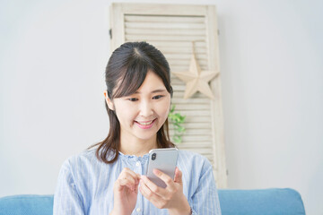 リビングで笑顔でスマホを使う女性