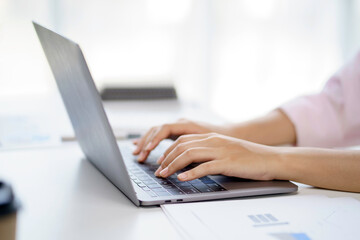 Close up of woman hand printing using laptop computer on the desk in the office.
