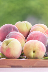 Fresh Sweet Peach on green bokeh background, Pink and yellow Peach fruit with leaf on wooden plate.
