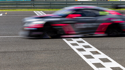 Race car blurred motion crossing the finish line on international circuit speed track, Motion blur Racing car crossing finish line on asphalt main straight racetrack.