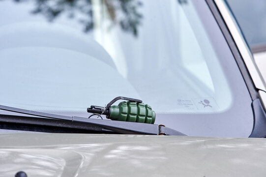 There is an airsoft fragmentation grenade on the windshield wiper of the car