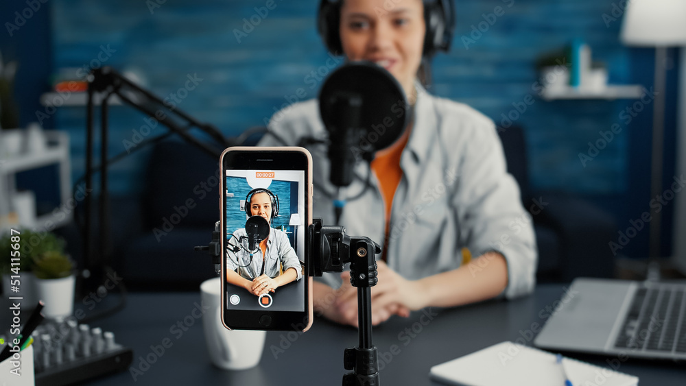 Poster popular internet star using portable computer while streaming remote podcast show on smartphone. cre