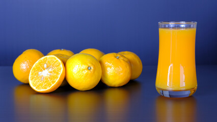 Close-up and vivid studio shot, a glass of orange juice, and a group of natural fresh oranges on...