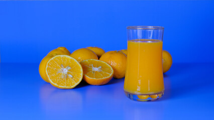 Close-up and vivid studio shot, a glass of orange juice, and a group of natural fresh oranges on a...