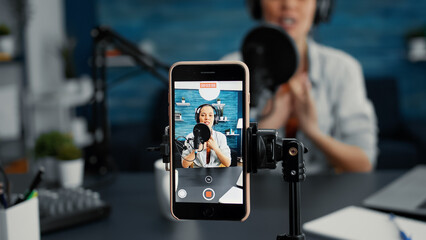 Modern smartphone recording vlogger talking to public while sitting at home studio desk. Famous...