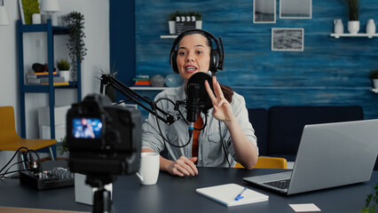 Famous internet podcaster getting ready for streaming while starting to discuss worldwide events with audience. Creative digital content creator sitting at home studio desk while putting on headphones
