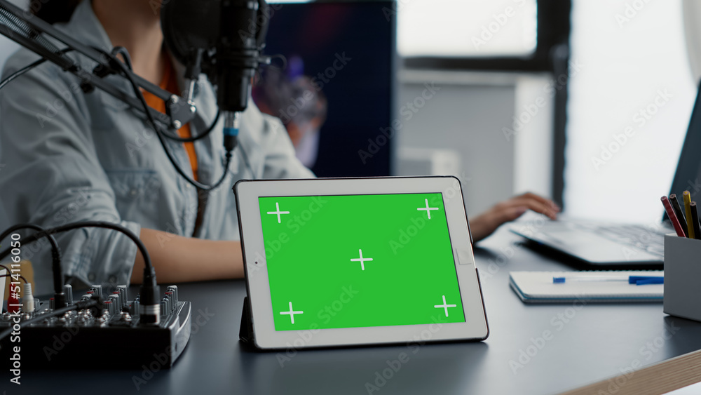 Poster tablet with chroma key with isolated background and mockup template standing on podcast studio desk.