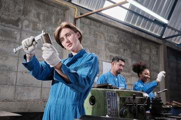 Young Caucasian female industry worker works with metalwork precision tools, lathe machines, and...