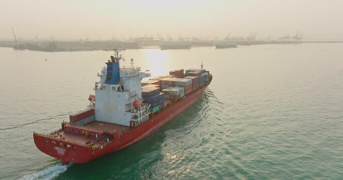 Aerial top view of cargo vessel ship carrying full of container sailing into the yard port at sunset. Concept freight shipping ship sea transport logistics import export.