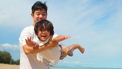 Happy family of dad carrying son flying play outside on the beach together having fun enjoy freedom...