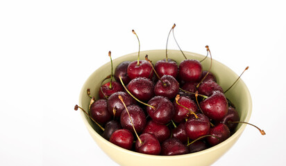 Ripe and juicy cherries in drops of water in a bowl on a white background. Horizontal orientation, copy space, close-up
