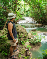 Thai guy Asian man backpacker men enjoying beautiful emerald waterfalls green forest mountains guiding for Thailand destinations camping hiking at Huai Mae Khamin waterfall national park, Kanchanaburi