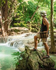 Thai guy Asian man backpacker men enjoying on beautiful emerald waterfalls green forest mountains guiding for Thailand destinations camping hiking at Erawan waterfall national park, Kanchanaburi.