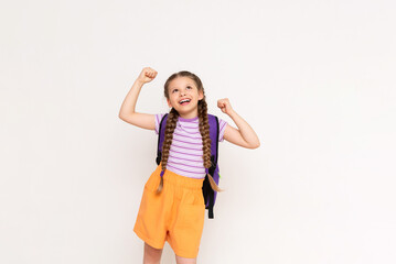 The child is very happy about the summer educational courses for children. A beautiful little girl holds up her fists and smiles broadly on a white isolated background.