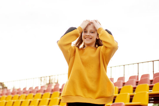 A smiling teenage girl on the background of the stands of the school stadium