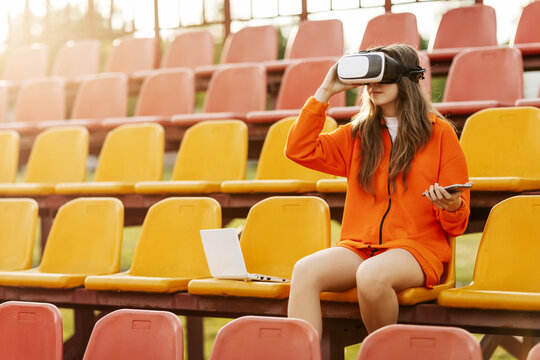 A young athlete wearing virtual reality glasses, dressed in sportswear, trains with a virtual simulated world. Technology of the future