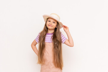 A beautiful little girl in a sundress and a straw hat is getting ready for a summer vacation. Summer holidays for children. White isolated background.