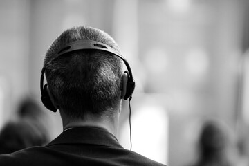 Shallow depth of field (selective focus) details with a caucasian man wearing translation headset...