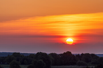 Colorful sunrise over trees, fields and village in spring in Ukraine