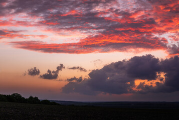 Sun sitting on the horizon against the background of colorful clouds in the sky 