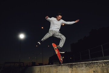 Fototapeta na wymiar Portrait of cool dude doing stunts on skateboard at night at skateboard there are no people.