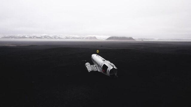 1973 U.S. Navy DC plane crash on remote black sand beach with mountains and low cloud drone view - Slheimasandur, Iceland