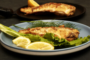 fried fish with lemon and herbs on a plate on the table