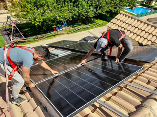 installation of solar panels on the roof of a house, partners. Real father and son teamwork