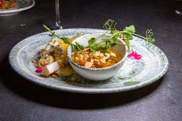 Delicious cheese platter - slices of several types of hard and soft cheese served on plate with honey, walnuts and sprig of peas