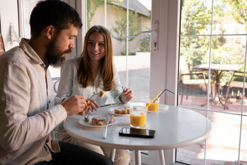 Beautiful couple having breakfast in a stylish cozy cafe, healthy family breakfast