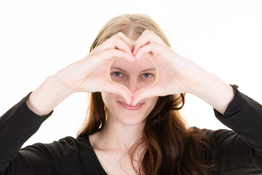young woman in love forms a heart with her hand fingers in front of her face eyes