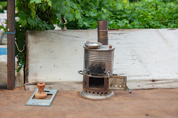 A smoky Turkish samovar with an open stove door stands in the courtyard of the house
