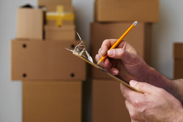 Man mover in uniform making notes on clipboard, close up
