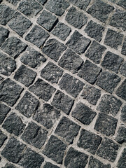 Texture of dark gray granite paving stones, top view. Background from natural vintage block stone.